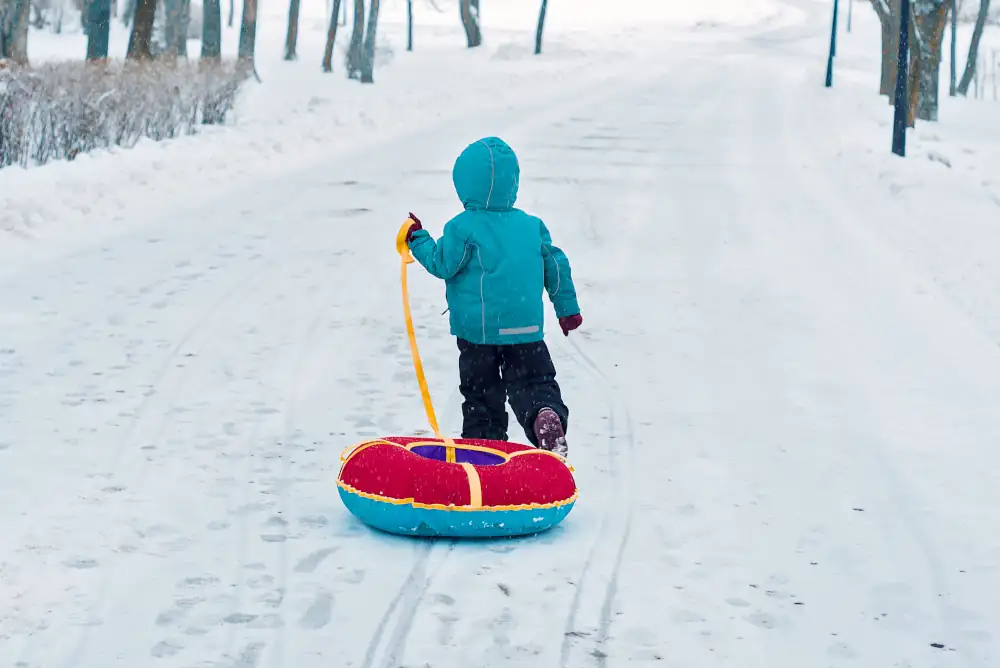 Dziecko z dmuchanym kołem do zjeżdżania po śniegu
